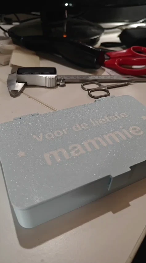 Het gesloten lichtblauwe doosje met kliksluiting en Voor de liefste mammie op het deksel